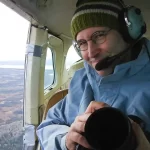 Garth Lenz can be seen here in a helicopter while on a conservation photography assignment. Garth is an acclaimed landscape photographer and conservation photographer who guides as a photography instructor for Nature Talks UK.